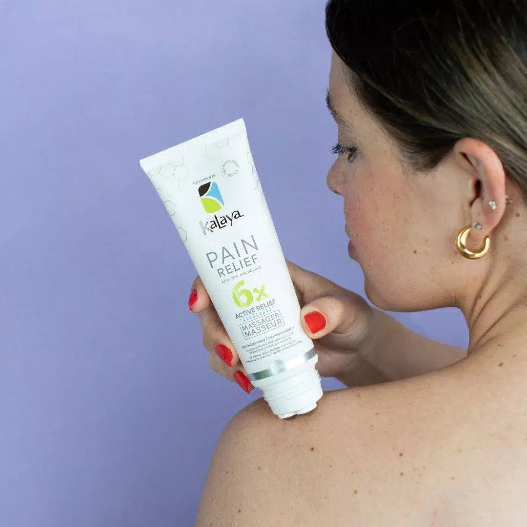 Woman rubbing pain relief cream roller applicator into shoulder for back and neck pain